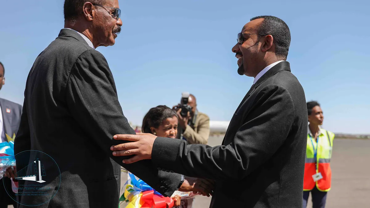 Isaias Afwerki y Abiy Ahmed se dan la mano sonrientes en la pista de un aeropuerto, en marzo de 2019